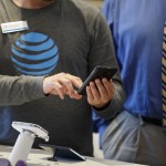 An employee helps a customer with a smartphone at an AT&T Inc. store in Newport Beach, California, U.S., on Thursday, Aug. 10, 2017. AT&T Inc. shares surged the most in more than eight years after the telecommunications giant posted a surprise wireless subscriber gain in the second quarter, showing it can fend for itself in a cutthroat price war. An offer for unlimited wireless data, bundled with discounted streaming-TV service, helping AT&T bide its time while awaiting regulatory approval to transform into a media powerhouse through the $85.4 billion purchase of Time Warner Inc. Photographer: Patrick T. Fallon/Bloomberg via Getty Images