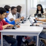 A multi-ethnic group of high school teenagers are working on digital tablets in the computer lab of the school.