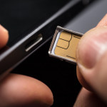 Close-up Of A Person Inserting A Sim Card Into The Back Of A Mobile Phone