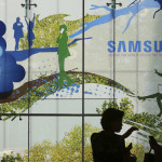 Visitors are silhouetted at Samsung Electronics shop in Seoul, South Korea, Friday, July 5, 2019. Samsung Electronics Co. said Friday its operating profit for the last quarter likely fell more than 56% from a year earlier amid a weak market for memory chips. (AP Photo/Ahn Young-joon)