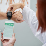 Doctor showing senior patient how to synchronize health app in smartphone and smartwatch
